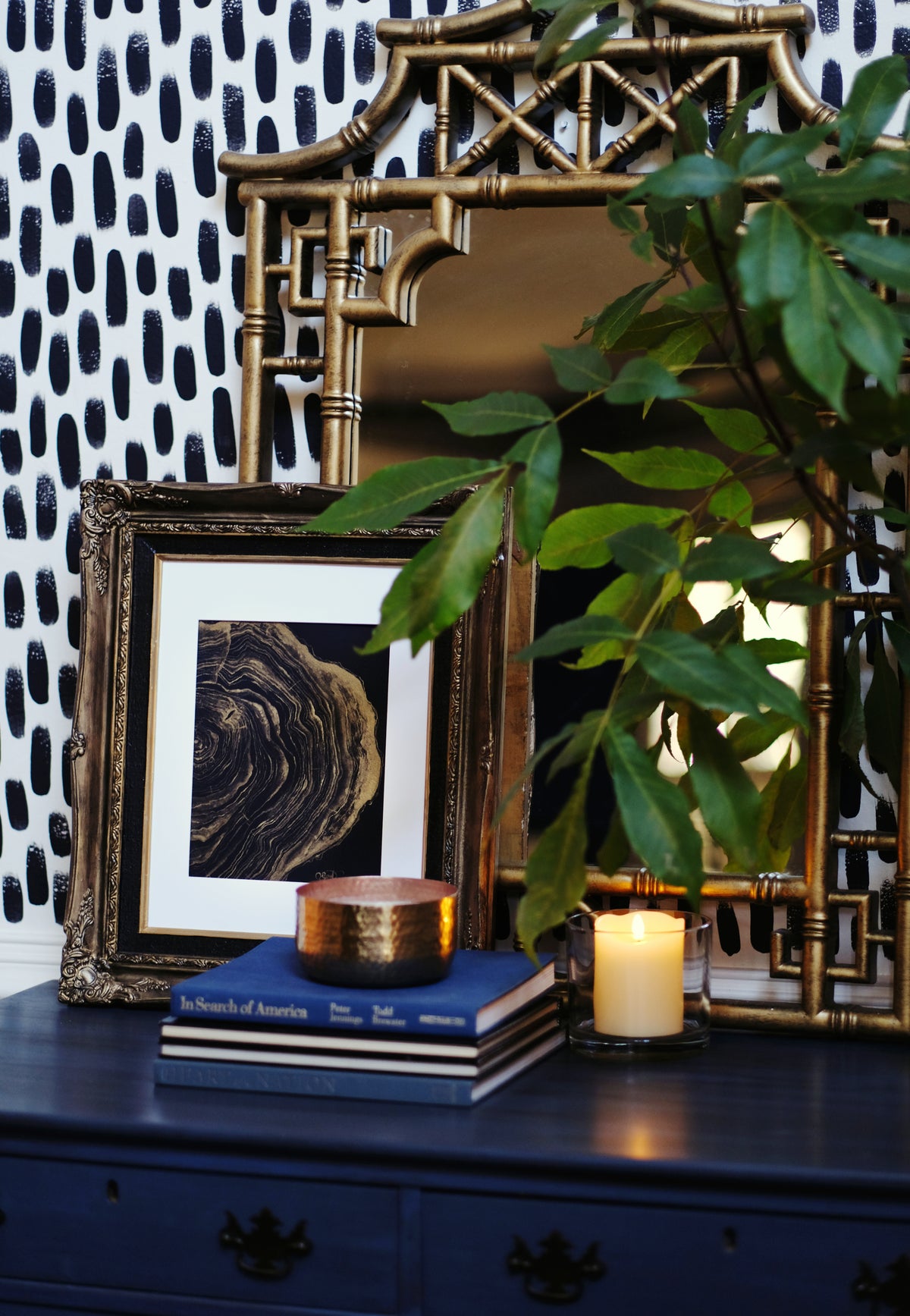 The Stories She Could Tell gold tree ring print in a dark frame with books and a candle