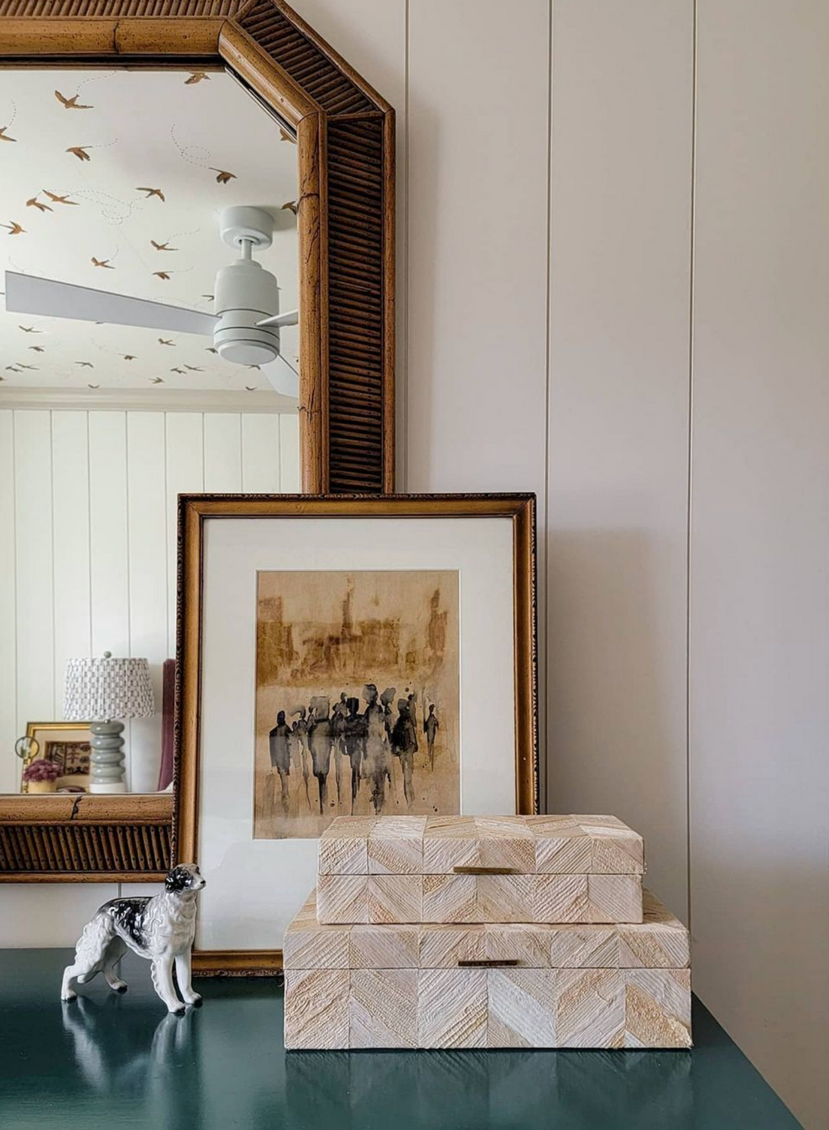 Busy City print in a gold frame on a dresser with bone boxes